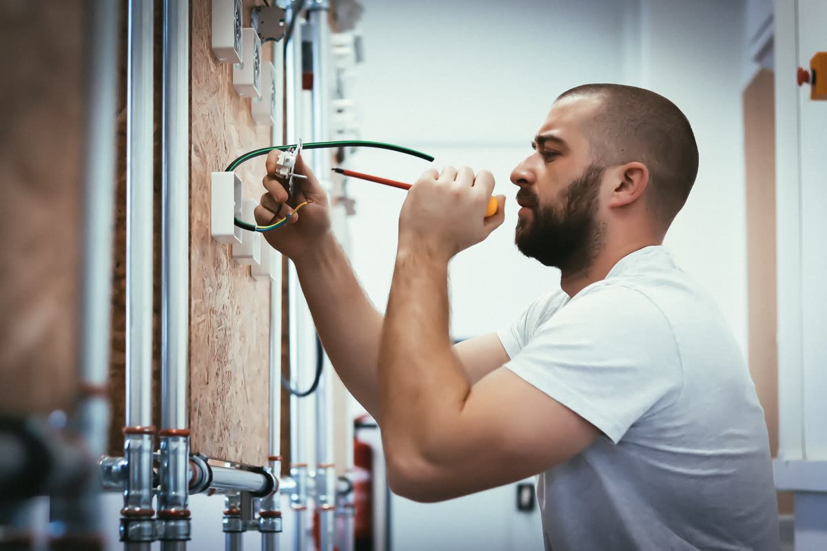 Účastník kurzu Voltimo měří napětí na výukovém elektro panelu